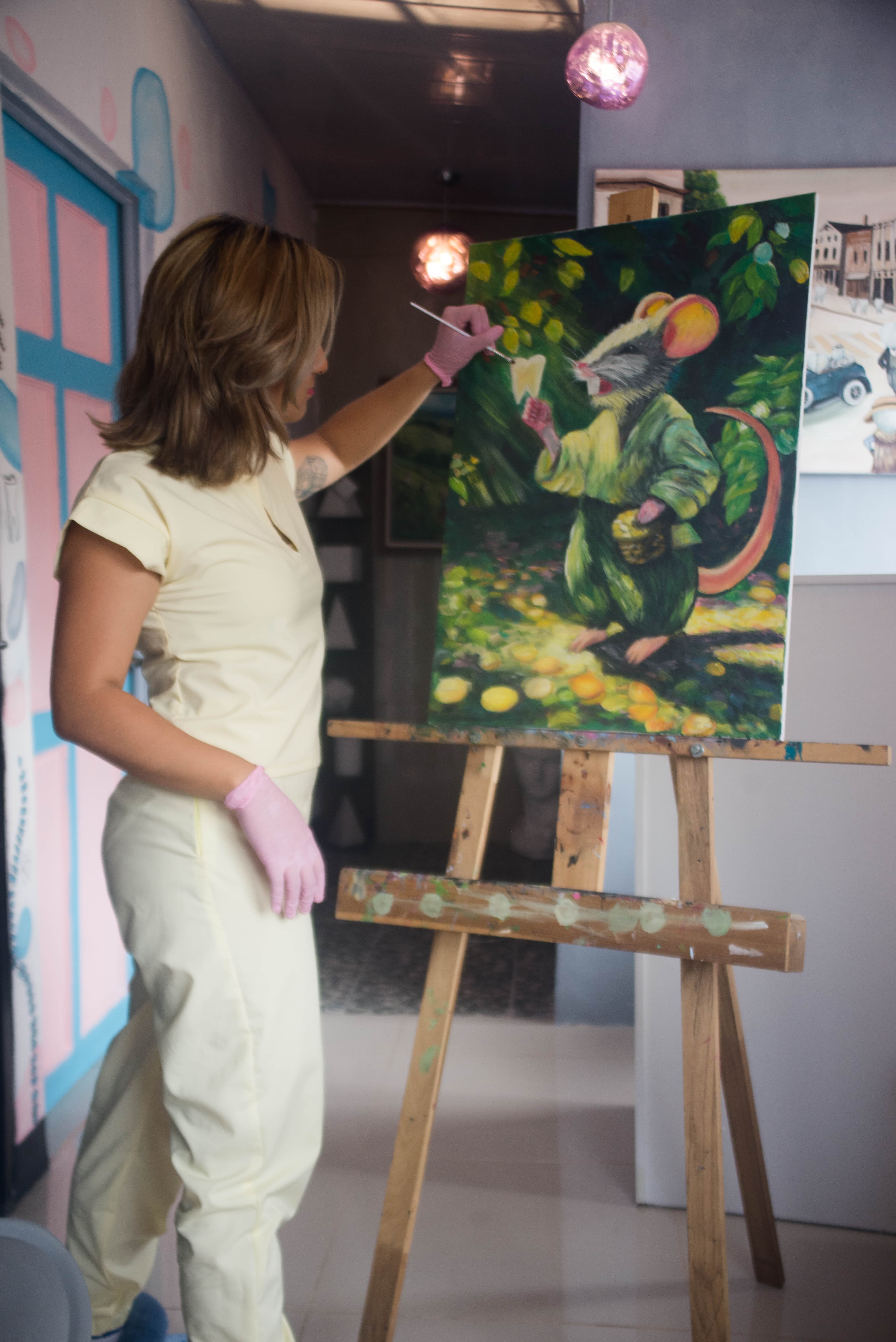 La Dra. Yorgeli González pintando una obra en un caballete dentro de Clínica Dental D'Arte